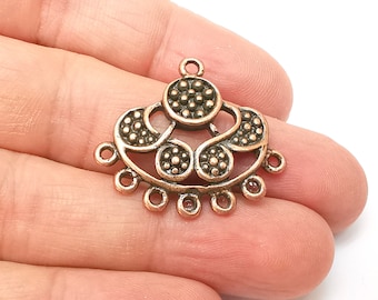 May include: A copper-colored metal pendant with a decorative design featuring a circle with smaller circles around it. The pendant has a loop at the top for attaching to a chain or cord.