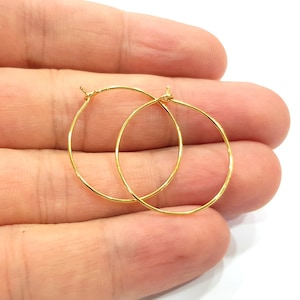 May include: A pair of gold hoop earrings. The earrings are simple and delicate, with a smooth finish.