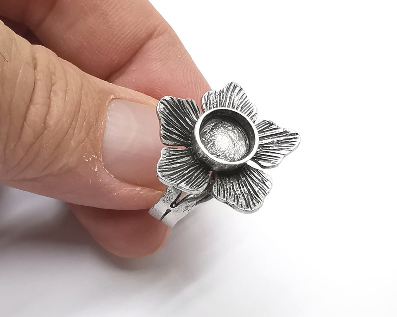 Op de afbeelding: Zilveren bloemenring met een ronde, open bezel om een cabochon of andere versiering toe te voegen.