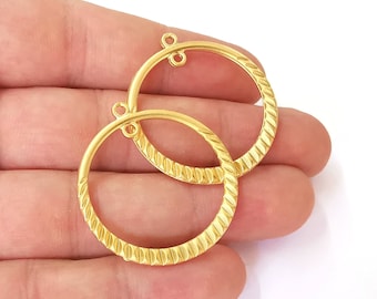 May include: Two gold-toned metal hoops with a textured surface. The hoops have a small loop at the top for attaching to earrings.