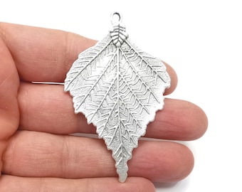 May include: Silver pendant in the shape of a detailed leaf with a textured surface.