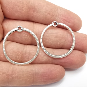 May include: Two silver-toned metal hoops with a hammered texture. The hoops are approximately 3.8 cm in diameter.