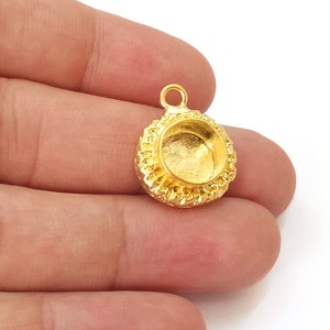 May include: Gold-toned pendant with a round, textured bezel setting. The pendant has a loop at the top for attaching to a chain or cord.
