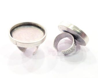May include: Two silver ring blanks with round, flat tops. The tops are smooth and have a slight shine. The rings are adjustable and have a textured band.