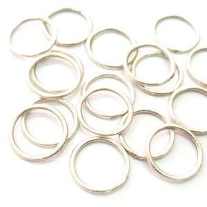 Puede incluir: Un montón de anillas de salto de plata, un tipo de hallazgo de joyería utilizado para conectar cadenas, cordones y otros componentes de joyería.