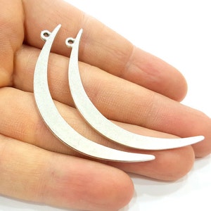 May include: Two silver crescent moon shaped metal charms with a hole at the top for attaching to jewelry or other crafts.