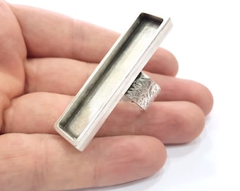 May include: A silver ring with a rectangular, open-top bezel. The bezel is designed to hold a resin or other material.