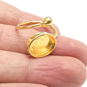 May include: Gold ring with a round, open bezel setting. The ring is designed to be worn on the knuckle of the finger.