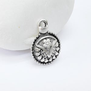 Puede incluir: Encanto de plata con un diseño floral. El encanto tiene un bucle en la parte superior para sujetarlo a un collar o pulsera.