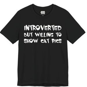 以下が含まれることがあります： 「INTROVERTED BUT WILLING TO SHOW CAT PICS」の白文字がプリントされた黒いTシャツ。クルーネックと半袖です。ブランドロゴ「GG」が中央上部にあります。