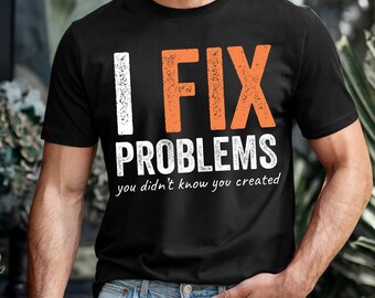 Puede incluir: Camiseta negra con el texto "I FIX PROBLEMS you didn't know you created" en letras blancas y naranjas. La camiseta es de cuello redondo y se está usando.
