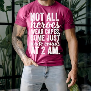 May include: A maroon t-shirt with the text "NOT ALL heroes WEAR CAPES, SOME JUST write emails AT 2 AM." The shirt is being worn by a person in light blue jeans.