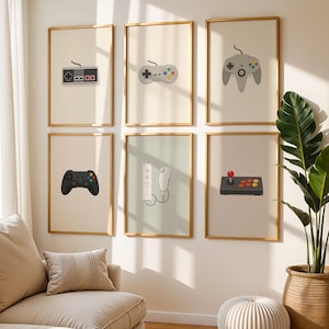 May include: Six framed art prints showcasing minimalist illustrations of video game controllers. The controllers are in various styles and colours, including a classic grey controller and a black controller.