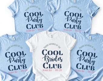 Puede incluir: Cinco camisetas azul claro y blancas con el texto "Proud Member of the Cool Party Club" y "Cool Brides Club". Las camisetas tienen cuello redondo y mangas cortas. El texto está en una fuente de escritura azul oscuro.