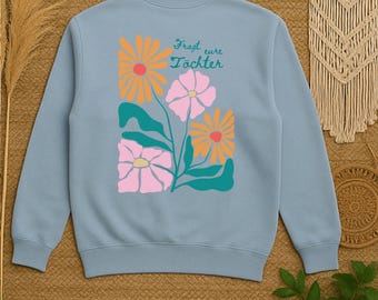 Puede incluir: Sudadera azul claro con un diseño floral. El diseño incluye flores naranjas y rosas, hojas verdes y el texto alemán "Fragt eure Töchter". La sudadera tiene cuello redondo.