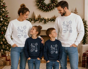 May include: Matching crewneck sweatshirts in white and navy blue featuring a dark or white line-art graphic of a gingerbread person, Christmas tree, sleigh, and gift box with the text Family Muller Christmas Era 2026 printed on the front.