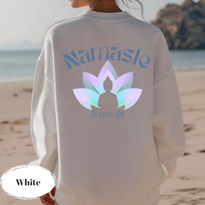 May include: White sweatshirt with the word "Namaste" in light blue script above a lotus flower design with a Buddha silhouette. The text "All damn day" is below the design. The word "White" is at the bottom.