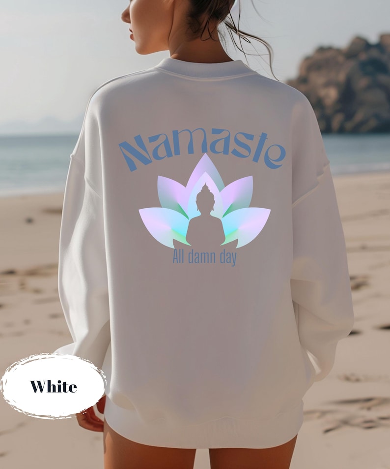 May include: White sweatshirt with the word "Namaste" in light blue script above a lotus flower design with a Buddha silhouette. The text "All damn day" is below the design. The word "White" is at the bottom.