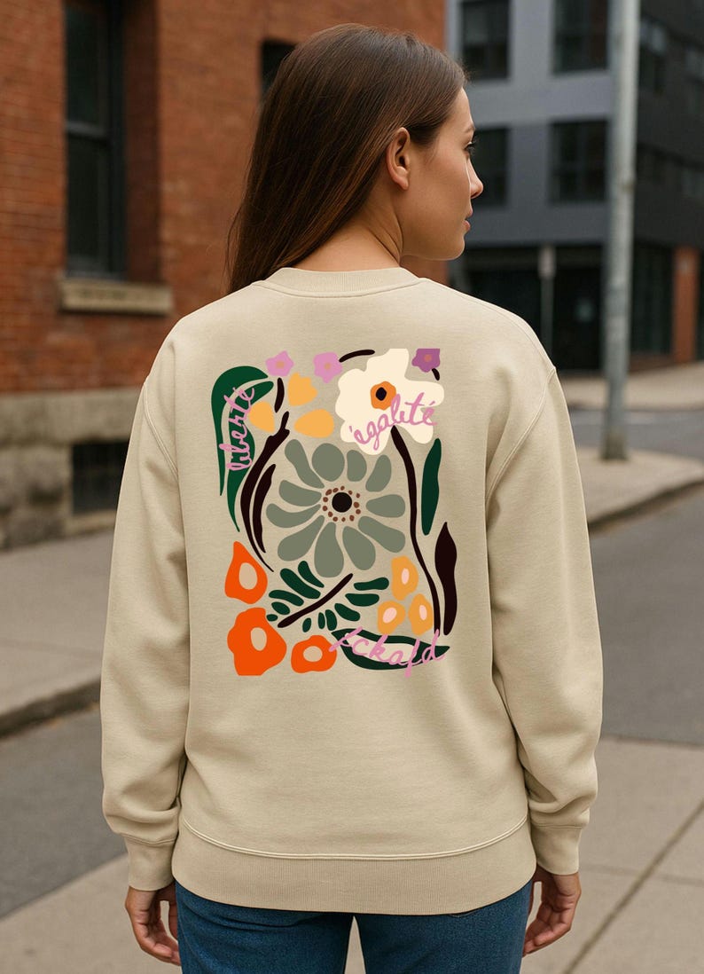 May include: Beige sweatshirt with a colorful floral design on the back. The design includes flowers in shades of green, orange, and purple, with the word "egalite" in cursive.