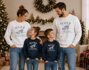 May include: Matching long-sleeve crewneck sweatshirts in white and navy blue, each featuring a graphic of a vintage truck carrying a Christmas tree, with the text MAIER, EST 2026, Family Christmas, and BERLIN - WINTER WONDERLAND printed on the front.