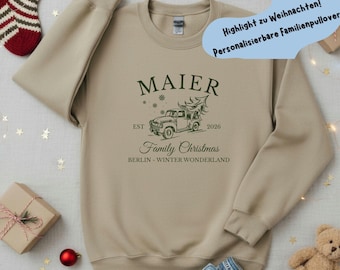 May include: A beige crewneck sweatshirt featuring a dark green graphic of a vintage pickup truck carrying a Christmas tree. The text reads MAIER, EST 2026, Family Christmas, and BERLIN - WINTER WONDERLAND, accompanied by small snowflake icons.