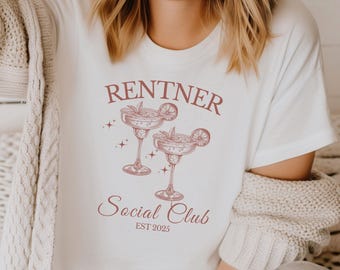 Puede incluir: Una camiseta blanca de manga corta con un gráfico granate de dos copas de margarita con rodajas de lima y el texto RENTNER Social Club EST 2025. El diseño incluye pequeños detalles de estrellas que rodean las dos copas en la parte frontal.