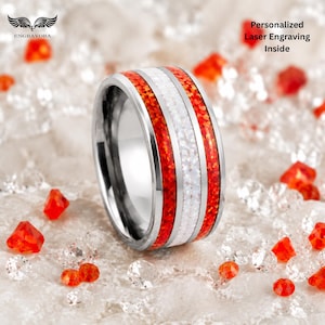 Puede incluir: Un anillo de tono plateado con una incrustación central blanca flanqueada por dos bandas rojas vibrantes. El texto 'Personalized Laser Engraving Inside' es visible en la esquina superior derecha y la marca 'ENGRAVORA' aparece arriba a la izquierda.