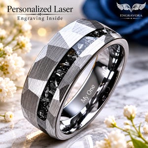 Puede incluir: Un anillo plateado con un diseño geométrico y una incrustación negra. El anillo tiene grabadas las palabras "My One" en el interior. También se ve el texto "Personalized Laser Engraving Inside".