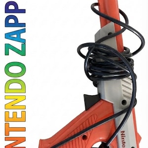 May include: A Nintendo Zapper light gun controller featuring a two-tone orange and gray plastic body with a black cord wrapped around the barrel and handle. The word Nintendo is printed on the side, and the text NINTENDO ZAPPER appears vertically.