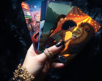 Può includere: Un set di carte dei tarocchi con illustrazioni colorate. Le carte mostrano una donna con i capelli scuri e un leone. Le carte sono tenute in una mano con un anello e un braccialetto d'oro.