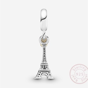 May include: A silver charm featuring the Eiffel Tower. The charm is detailed with intricate architectural elements and hangs from a silver loop. The charm is marked with "925" and "Sterling Silver".