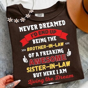May include: A brown t-shirt with white and red text that reads "Never Dreamed I'd End Up Being The Brother-in-Law of a Freaking Awesome Sister-in-Law But Here I Am Living the Dream." The shirt has a crew neck and short sleeves.