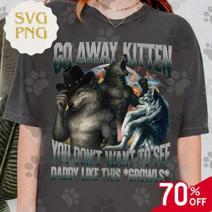 May include: Dark gray t-shirt featuring a graphic of three wolves with the text "GO AWAY KITTEN" and "YOU DON'T WANT TO SEE DADDY LIKE THIS *GROOWLS*". The design includes a cowboy hat and lightning effects. A 70% off sale tag is visible.