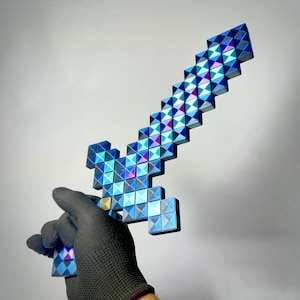 May include: A pixelated sword with a blue, purple, and silver iridescent finish. The sword is held by a gloved hand. The sword's design is reminiscent of a video game.