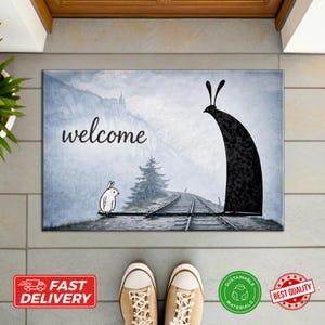 May include: Rectangular welcome mat with a whimsical design. It features a black silhouette and a bunny, set against a scenic backdrop with a railway track and the word "welcome". The mat is placed in front of a door.