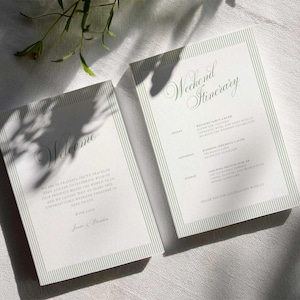 Puede incluir: Dos tarjetas blancas de itinerario de eventos con bordes a rayas verdes y escritura elegante. Una tarjeta dice "Bienvenida" y la otra "Itinerario de fin de semana". Las tarjetas est&aacute;n sobre una superficie blanca texturizada con sombras.