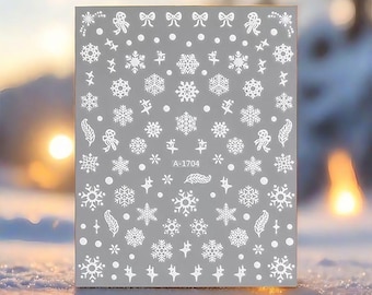 Puede incluir: Hoja de pegatinas para decoración de uñas con temática invernal. Las pegatinas blancas presentan copos de nieve, lazos, estrellas y otros diseños festivos sobre un fondo gris. El texto "A-1704" está impreso.