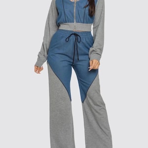May include: A two-piece outfit featuring a cropped zip-up jacket and wide-leg pants. The jacket has gray sleeves and a denim-look front with a sheer panel. The pants combine denim-look fabric with gray panels. A drawstring cinches the waist.