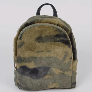 May include: A small, camouflage-patterned backpack with a faux fur texture. The bag features a gold-colored zipper, a black handle, and a rounded shape. The camouflage design incorporates shades of green, brown, and gray.