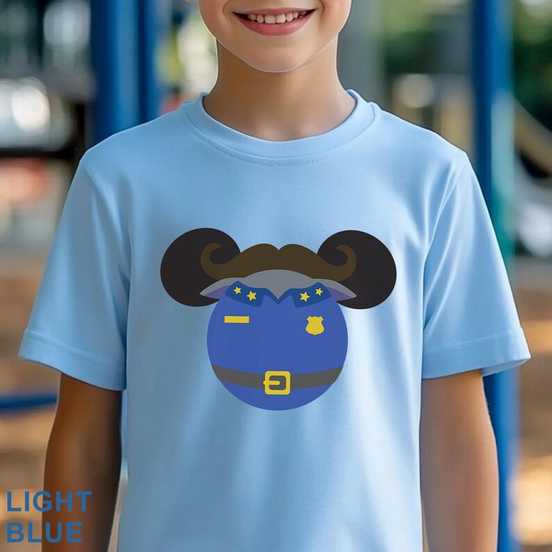 Puede incluir: Camiseta azul claro con un dise&ntilde;o de polic&iacute;a de dibujos animados. El dise&ntilde;o incluye una insignia azul, una hebilla dorada y un bigote marr&oacute;n. El texto "LIGHT BLUE" est&aacute; impreso en la parte inferior izquierda de la camiseta.