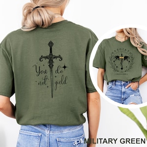 May include: Military green t-shirt featuring a black sword design with the words "You do not yield." The shirt also has a smaller image of a shirt with a dragon design. The shirt is made of a soft, comfortable material.