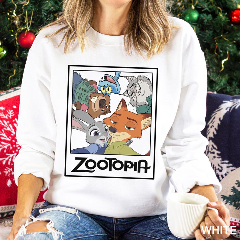Peut inclure: Sweat-shirt blanc avec un motif rectangulaire repr&eacute;sentant des personnages du film d'animation "Zootopia". Le motif comprend Judy Hopps, Nick Wilde et d'autres personnages. Le mot "Zootopia" est imprim&eacute; en noir.