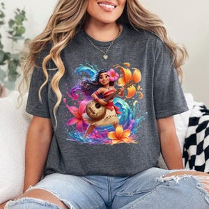 May include: Dark gray t-shirt featuring a vibrant illustration of a Polynesian woman playing a ukulele. The design includes colorful flowers, water splashes, and a tropical theme. The shirt is made of a soft material.