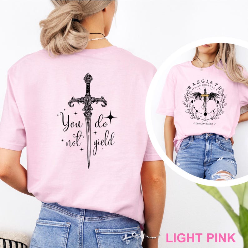 May include: Light pink t-shirts with black graphic designs. One shirt features a sword with the text "You do not yield." The other shirt has a circular design with text and a dragon.
