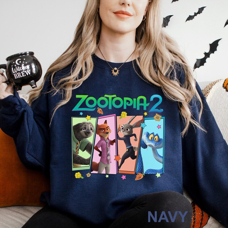 Może przedstawiać: Granatowa bluza z napisem "ZOOTOPIA 2" w kolorze zielono-białym. Projekt zawiera wizerunki postaci z filmu. Słowo "NAVY" jest wydrukowane na dole bluzy.