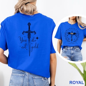 May include: Royal blue t-shirt with a black sword graphic and the text "You do not yield." A second image shows a similar shirt with a different graphic and text. The shirt is a short-sleeved crew neck.