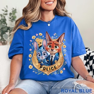 Peut inclure: T-shirt bleu roi avec une image de dessin anim&eacute; d'un renard et d'un lapin en uniforme de police &agrave; l'int&eacute;rieur d'un badge dor&eacute;. Le badge est entour&eacute; de fleurs et du mot "POLICE". Le texte "ROYAL BLUE" est en bas.