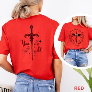 May include: Red t-shirts with black graphic designs. One shirt features a sword with the text "You do not yield." The other shirt has a circular design with the text "Basgiath War College" and "Dragon Rider V".
