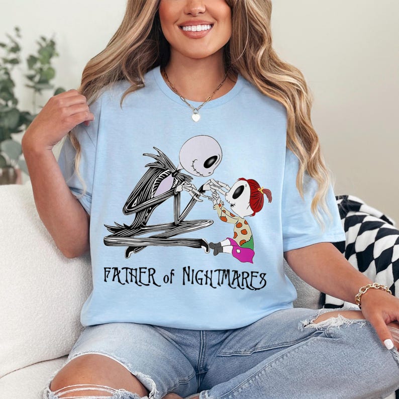 Puede incluir: Camiseta azul claro con una ilustraci&oacute;n de dibujos animados de Jack Skellington y un ni&ntilde;o de The Nightmare Before Christmas. El texto "FATHER of NIGHTMARES" est&aacute; debajo de la imagen.