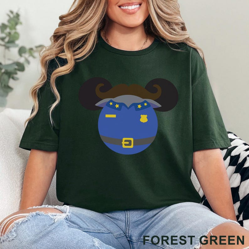 Puede incluir: Camiseta verde bosque con un dise&ntilde;o de polic&iacute;a de dibujos animados. El dise&ntilde;o incluye una cara azul con una placa, una hebilla dorada y un bigote marr&oacute;n. El texto "FOREST GREEN" est&aacute; en la parte inferior.